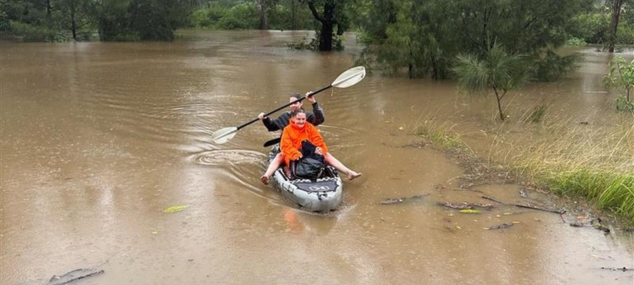 2 people on a kayak rowing through food water.